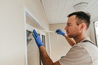 Homeowner applying weather stripping to exterior door